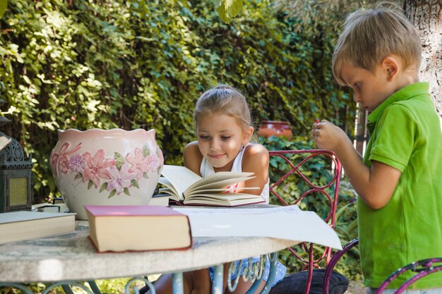 Kinderen lezen aan tafel in de tuin