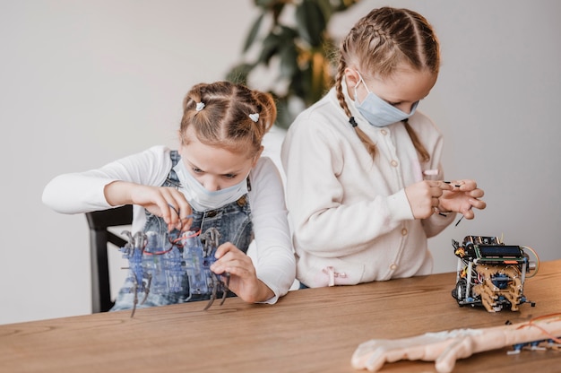 Kinderen met medische maskers leren hoe ze elektrische componenten moeten gebruiken