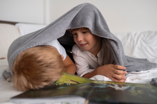 Gratis foto kinderen met tijdschrift binnenshuis vooraanzicht