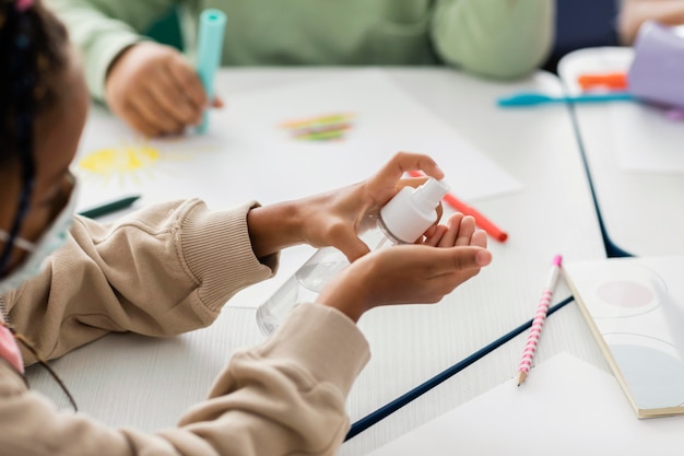 Kinderen ontsmetten hun handen in de klas