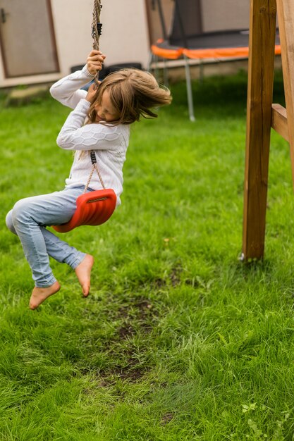 kinderen op de schommel. meisje swingende op een schommel in de tuin. zomerplezier.