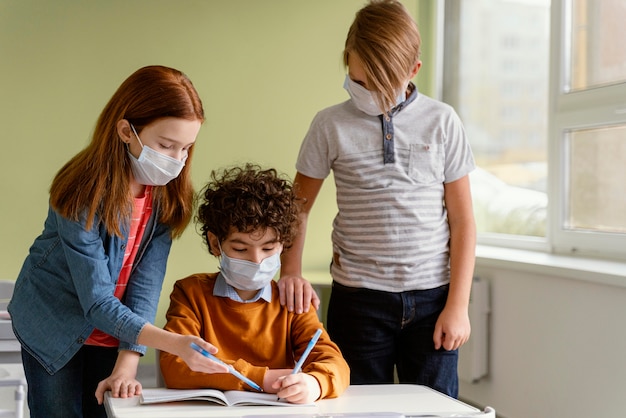 Kinderen op school die met medische maskers leren
