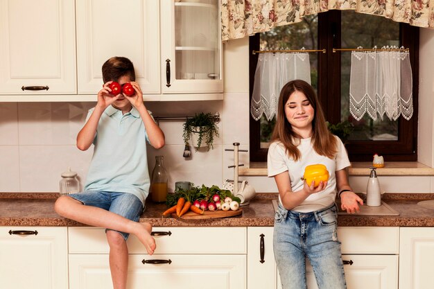 Kinderen poseren met groenten in de keuken