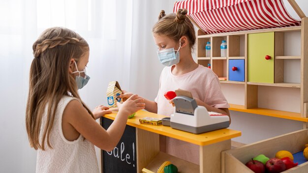 Kinderen spelen binnenshuis samen terwijl ze medische maskers dragen