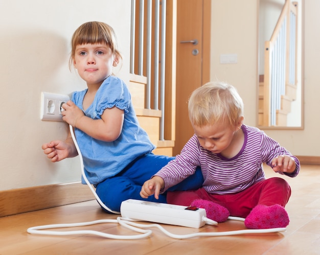 kinderen spelen met elektrische extensie en stopcontact