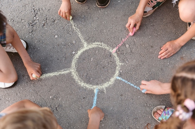 Kinderen tekenen een zon met krijt