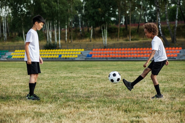 Kinderen voetballen onder toezicht van voetbaltrainer