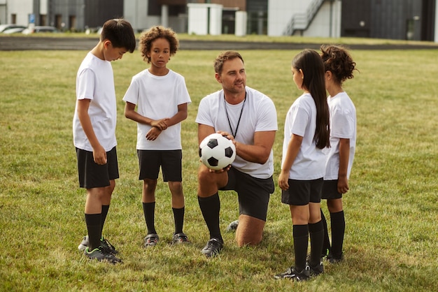 Kinderen voetballen onder toezicht van voetbaltrainer