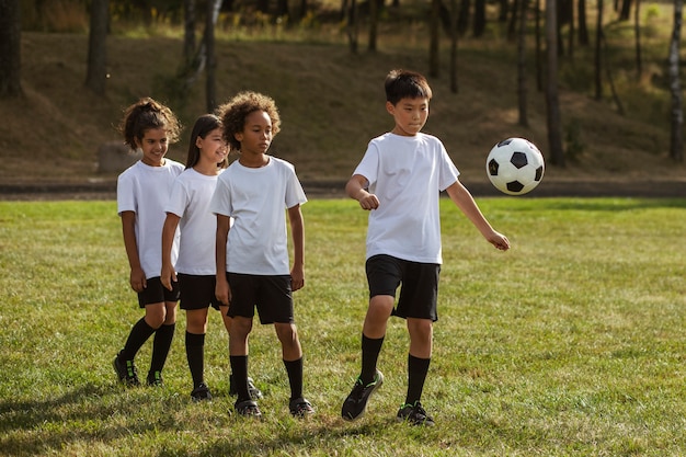 Gratis foto kinderen voetballen onder toezicht van voetbaltrainer