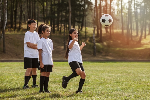 Kinderen voetballen onder toezicht van voetbaltrainer