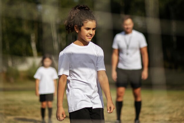 Kinderen voetballen onder toezicht van voetbaltrainer