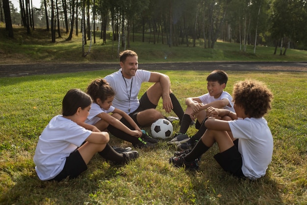 Kinderen voetballen onder toezicht van voetbaltrainer