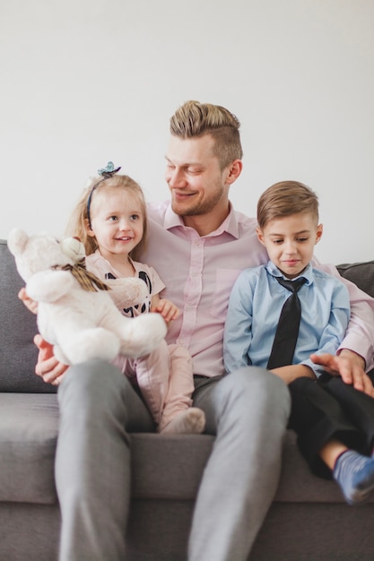 Gratis foto kinderen zitten met hun vader op de bank