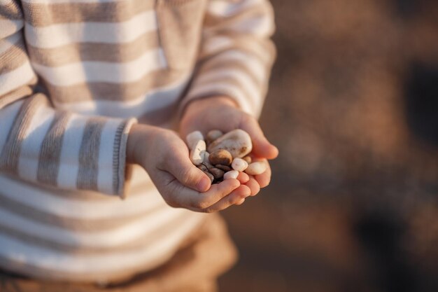 kinderhanden met rotsen in de buurt van de zee