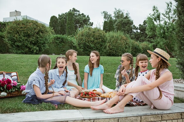 Kindermode concept. De groep van tiener meisjes zitten op groen gras in het park