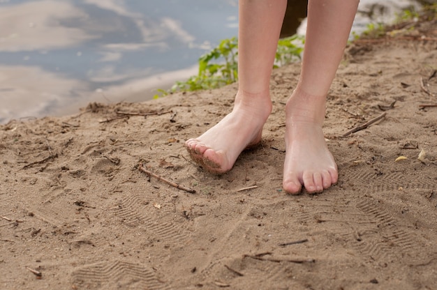 Kindervoeten op blote voeten close-up zonder sokken en schoenen op het zand op het strand