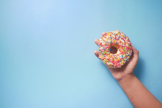Kindhand met verse donuts op blauwe ondergrond