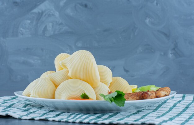 Kipnuggets en gekookte pasta op witte plaat.