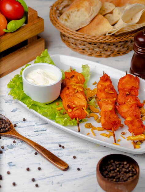 Kippenborst bbq, shish kebab met groenten, kruiden en sumakh en yoghurt in witte plaat.