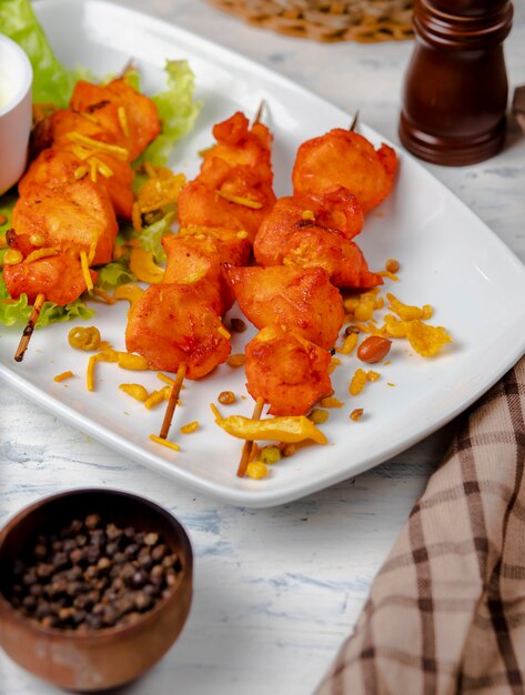 Kippenborst bbq, shish kebab met groenten, kruiden en sumakh in witte plaat.