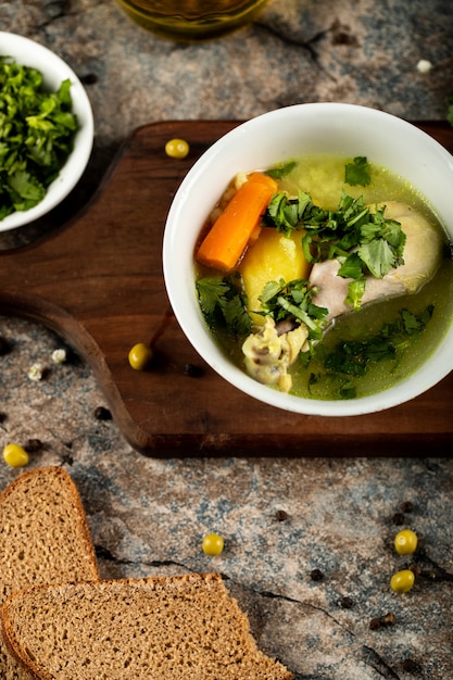 Kippensoep met kruiden en groene salade, in een witte kom