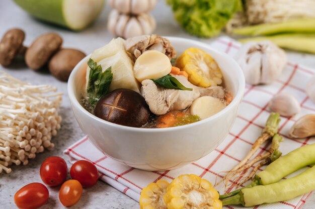 Kippensoep met maïs, shiitake-paddenstoel, enoki-paddenstoel en wortel.