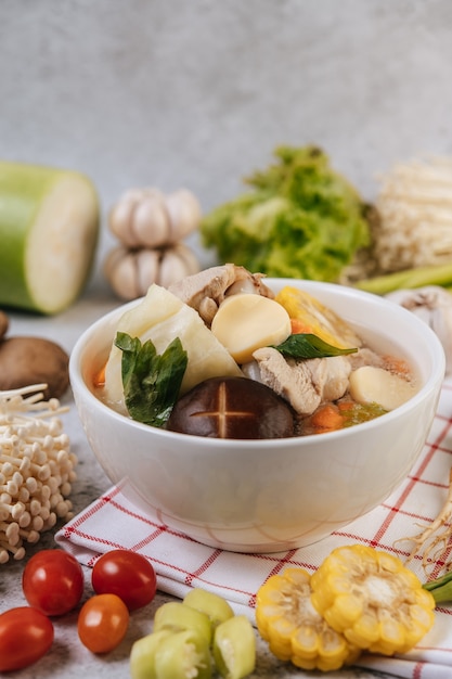 Kippensoep met maïs, shiitake-paddenstoel, enoki-paddenstoel en wortel.