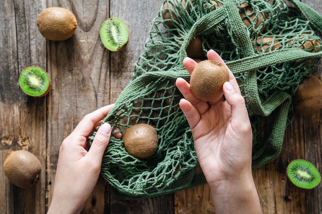 Kiwi in vrouwelijke handen een zicht op de top een vrouw stopt fruit in een touwtje