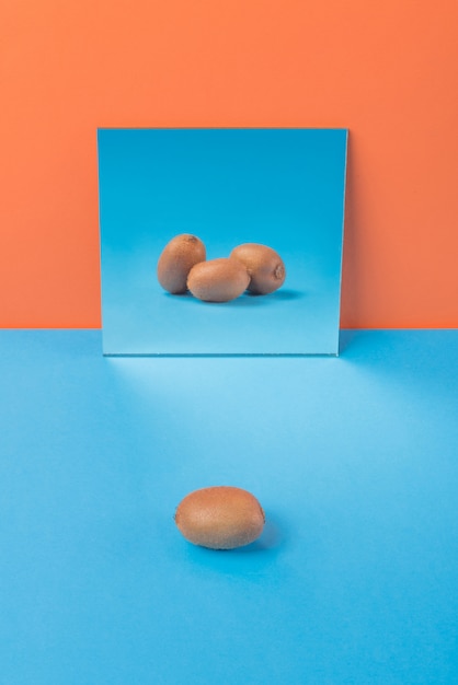 Gratis foto kiwi op blauwe tafel geïsoleerd op oranje