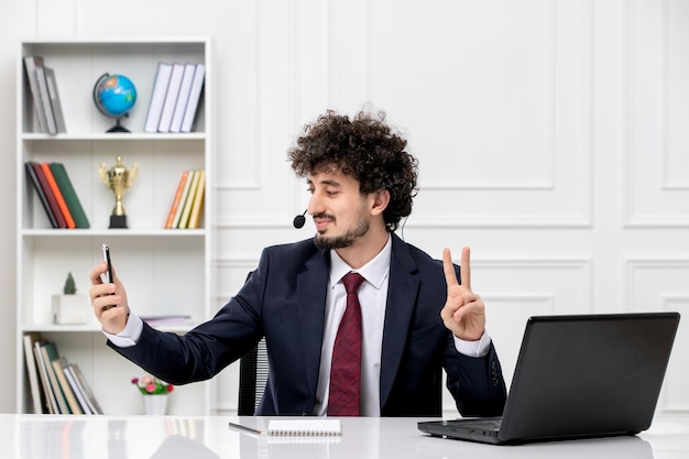 Klantenservice gekrulde brunette jonge man in kantoorpak met laptop en headset die selfie neemt