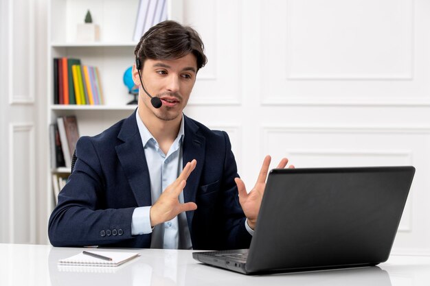 Klantenservice knappe kerel met headset en laptop in pak met serieuze videocall