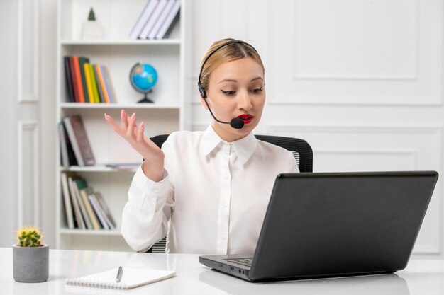 Klantenservice mooi blond meisje in wit overhemd met laptop en headset zwaaiende handen