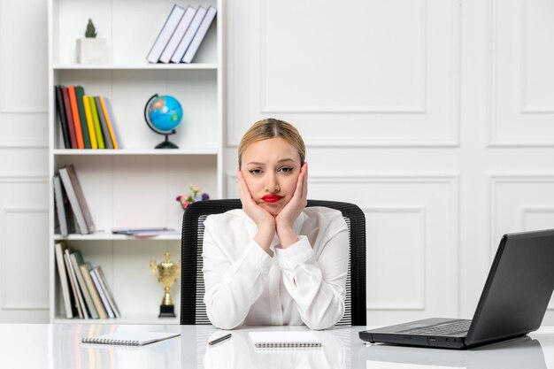 Klantenservice schattig meisje in wit overhemd met rode lippenstift en laptop moe met handen op kin