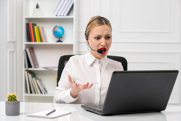 Klantenservice schattig mooi meisje in wit overhemd met computer en headset geïrriteerd tijdens een gesprek