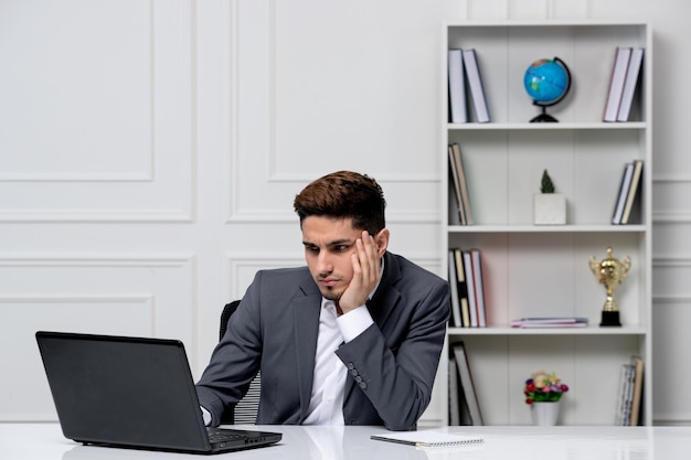 Klantenservice schattige knappe kerel in kantoorpak met computer kijken op een scherm en gefocust