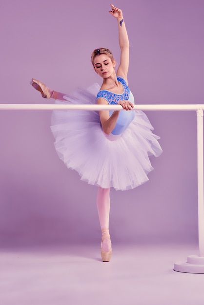 Gratis foto klassieke ballerina poseren op ballet barre