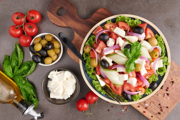 Klassieke griekse salade van verse groenten, komkommer, tomaat, paprika, sla, rode ui, fetakaas en olijven met olijfolie. Gezond eten, bovenaanzicht