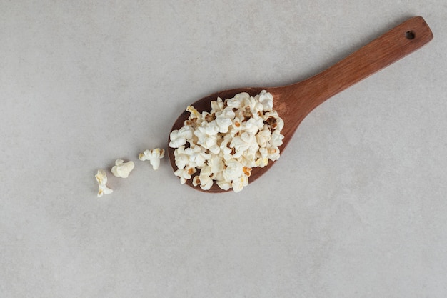 Klassieke op smaak gebrachte popcorn op een houten lepel op marmer.