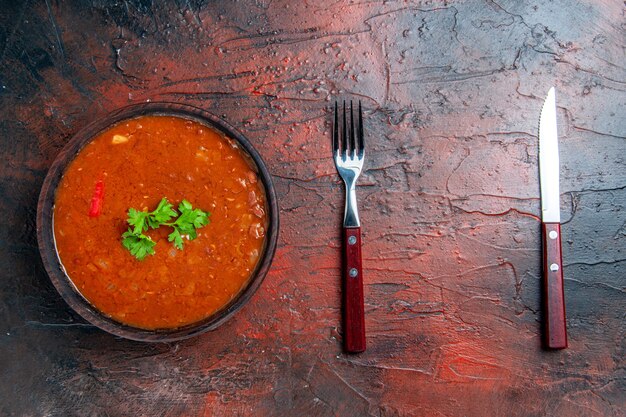 Klassieke tomatensoep in een bruine kom en lepel op gemengde kleurentafel