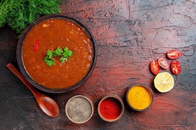 Klassieke tomatensoep in een bruine kom en verschillende kruiden op tafel met gemengde kleuren