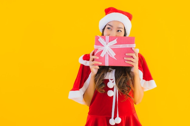 Kleding van portret de mooie jonge aziatische Kerstmis en hoedenglimlach gelukkig met rode giftdoos