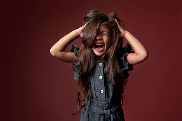 Klein Aziatisch meisje dat schreeuwt en haar handen in haar haar heeft
