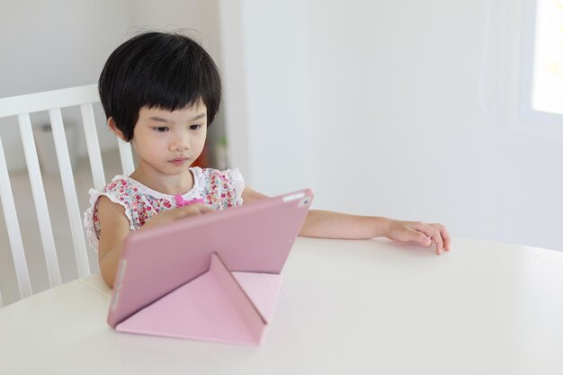 Klein aziatisch meisje dat thuis digitale tablet speelt