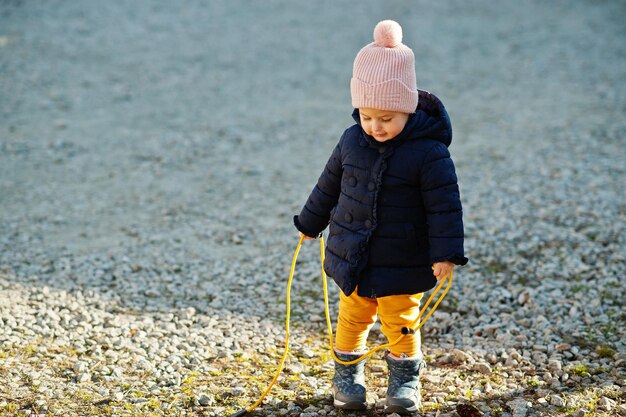 Klein babymeisje in de zon houdt touwsprong vast