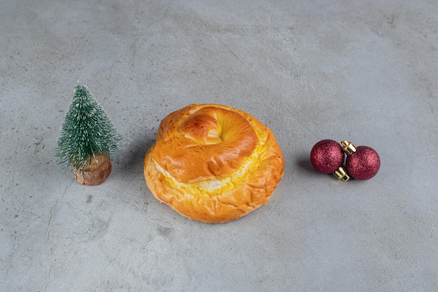 Gratis foto klein boombeeldje, zoet broodje en decoratieve ballen gerangschikt op marmeren tafel.
