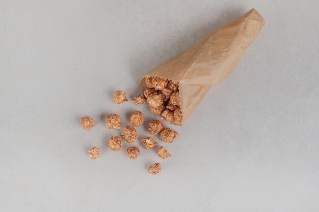 Klein deel van popcornsuikergoed in een papieren verpakking op marmeren tafel.