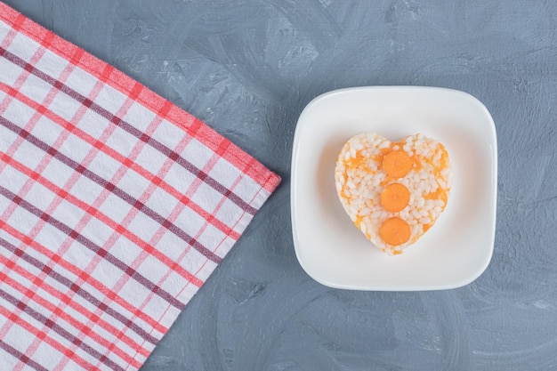 Klein gedeelte van gekookte rijst naast een handdoek op marmeren achtergrond.