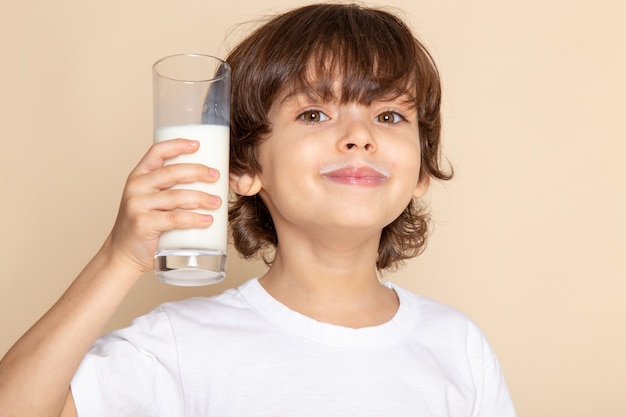 Klein kind schattig drinken hele witte melk lachend op roze