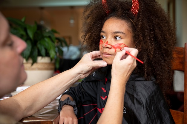 Gratis foto klein meisje bereidt zich voor op halloween met een duivelskostuum