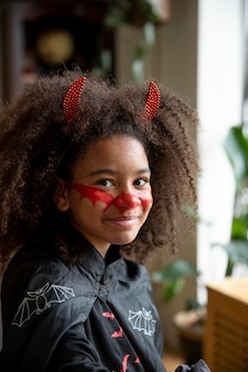 Klein meisje bereidt zich voor op halloween met een duivelskostuum
